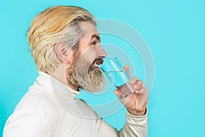 Male drinking from a glass of water. Health care concept, lifestyle, close up. Smiling male holding transparent glass in