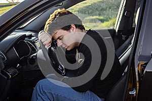 a young man is tired on the road and sleeps on the steering wheel of a car