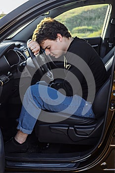 a young man is tired on the road and sleeps on the steering wheel of a car