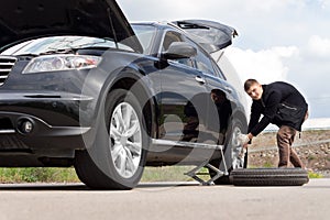 Male driver changing his tyre at the roadside