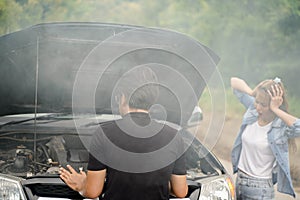 A male driver checks the condition of a car after an accident with an engine that smokes