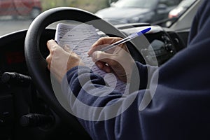 Male driver jotting down notes seated in a car photo