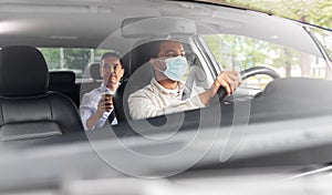 male driver in mask driving car with passenger