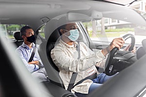 male driver in mask driving car with passenger