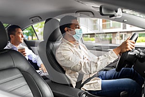 male driver in mask driving car with passenger