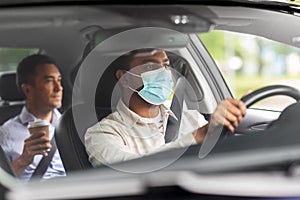 male driver in mask driving car with passenger