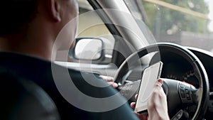 Male driver sitting in the car and holding smartphone with map gps navigation