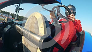 Male driver is sitting inside of a racing cart and managing it