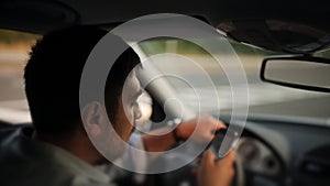 A male driver texting on a cellphone while driving