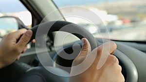 Male driving a car, his hands on steering wheel against windshield, close-up