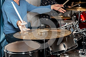 Male drum player hands holding cymbals with both hands and sticks. Drummer