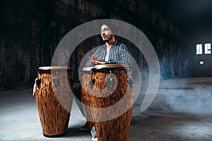 Male drummer plays on wooden drums in factory shop