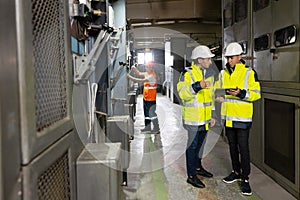 Male Electrical Engineers in Hard Hats Discuss New Project while Using Tablet Computer. They're Making Calculated