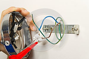 Male electrician connects the lamp on the wall