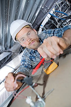 Male electrician fixing cables for light on ceiling