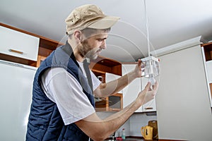 A male electrician fixing light on the ceiling.