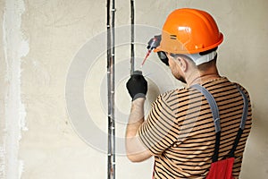 male electrician hands checks presence of electrical voltage in socket phase uses electrical tester screwdriver