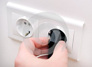 Male electrician inserting plug into socket in order to check its serviceability, closeup