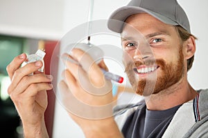 male electrician installing bulb in suspended light fitting