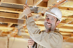 male electrician installing cabling into roof