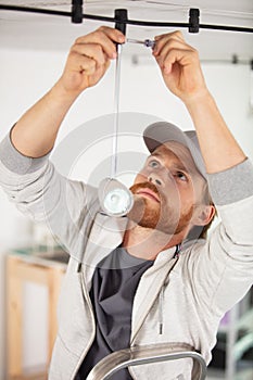 male electrician installing suspended light fitting