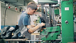 Male employee is cutting a boot out of a rubber sole