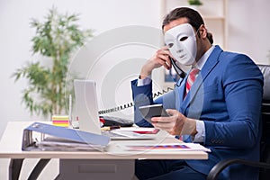 Male employee with mask in hipocrisy concept