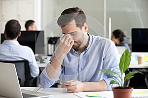 Male employee massage eyes having eye tension at workplace