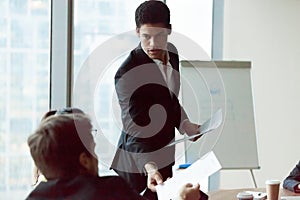 Male employee share handout material to colleagues at meeting photo