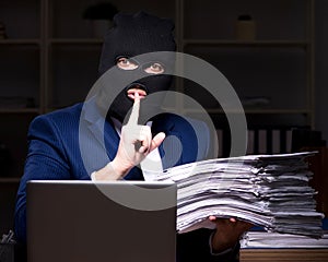 Male employee stealing information in the office night time