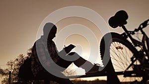 Male employee worker silhouette with digital tablet works remotely there is a bicycle nearby. Business concept modern