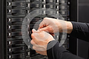 Male IT Engineer Adjusting Hard Drives In SAN At Datacenter