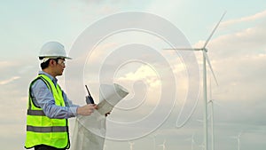 Male engineer analyze a blueprint drawing of wind turbine farm