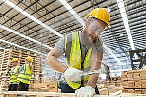 Male engineer carpenter wearing safety uniform and yellow hard hat working using hammer nail to on wood at workshop manufacturing