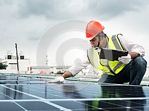 Male engineer checks a photovoltaic solar plant and uses a recording tablet. mechanic in protective helmet. Man in uniform