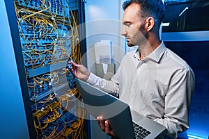 Male IT engineer connecting cable to server rack