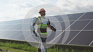 Male engineer in exoskeleton walking on solar plant
