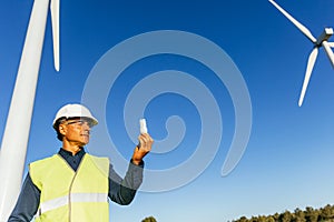 Male engineer holding a light bulb while standing in wind turbine field.
