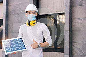 Male engineer holds the solar panel and thumbs up