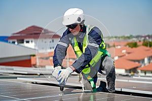 Male engineer maintaining solar cell panels on building rooftop. Technician working outdoor on ecological solar farm construction.