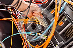 Male IT Engineer Plugging High Speed Fiber Cable In Network Switch