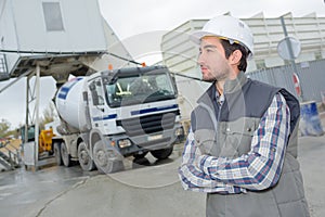 Male engineer standing in front truck on building site