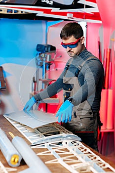 Male engineer or technician working on drone details in lab. Aircraft capable of GPS surveillance. Carbone wing.