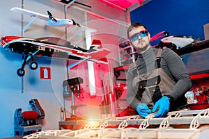 Male engineer or technician working on drone details in lab. Aircraft capable of GPS surveillance. Carbone wing.