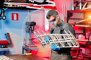 Male engineer or technician working on drone details in lab. Aircraft capable of GPS surveillance. Carbone wing.