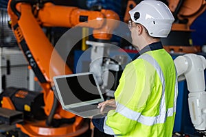 Male engineer using laptop control and checking system robot arm automate. robotic automation in line production at industrial.