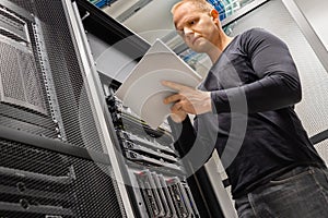 Male IT Engineer Using Tablet In Datacenter to Monitor Network and Servers