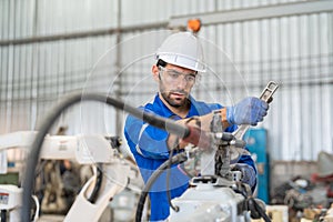 Male engineer using wrench tool repair robot arm welding machine in factory