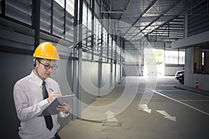 Male engineer writing in factory With note on notepad or industry blurred background