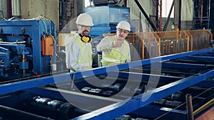 Male engineers at industrial factory. Two experts are observing a rolling conveyor